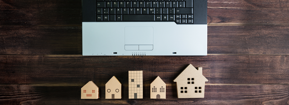Casas modelo de madera junto a una computadora portátil